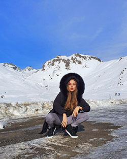Fotografía de modelo Xenia Tchoumitcheva, cabello natural negro, formaciones montañosas: pelo negro,  Chaqueta blanca  